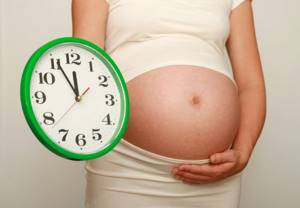 беременная держит часы