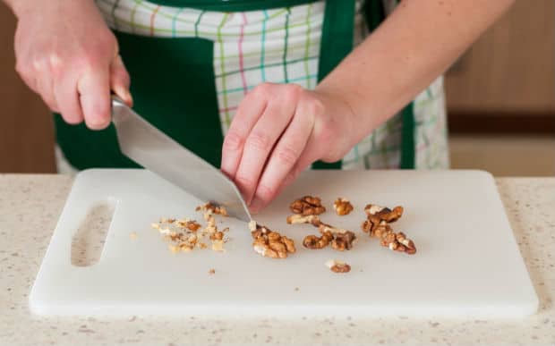 pieces of walnuts with a knife on a cutting board