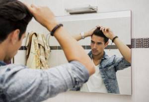 Man combing his hair in front of a mirror