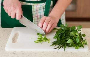 fresh parsley with dill on a cutting board with a knife on the table