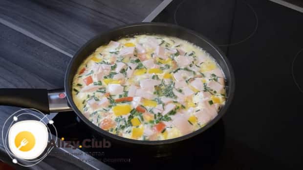 A delicious omelette with sausage cooked in a frying pan is ready.